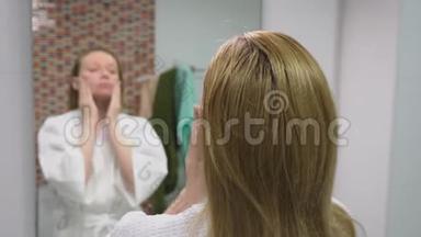面子的关怀观念.. 女人用化妆水在浴室里照顾皮肤。 上午卫生